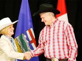 Alberta Premier Rachel Notley, left, greets Prime Minister Stephen Harper with a handshake in Calgary on July 6, 2015. Notley is trying to stay out of the fray of the federal election despite Harper’s remarks about her government’s tax policies during a campaign stop this week.