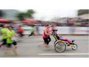 Chandra Round (in wheelchair) with Ashley Burns and Nicole Pollock participate in the half-marathon portion of the Edmonton Marathon on Jasper Avenue on Aug. 24, 2014.