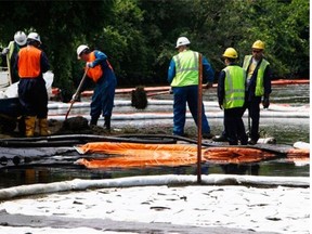 Crews clean up oil from a ruptured pipeline, owned by Enbridge Inc., near booms and absorbent materials where Talmadge Creek meets the Kalamazoo River in Marshall Township, Mich., on July 30, 2010. Before expanding oilsands production, writes Arthur Hoole, companies should keep in mind one of the largest, most expensive inland oil spills in U.S. history.