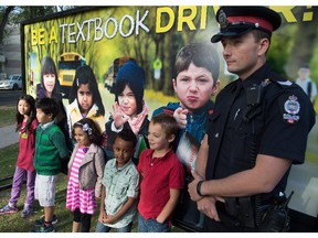 Sergeant David Green, Edmonton Police Service with the new billboard and kids from Mother Teresa Catholic School as Edmonton Police Service launches the second year of their Textbook Driver public awareness campaign in Edmonton. Aug. 31, 2015.