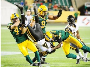 Edmonton Eskimos linebacker J.C. Sherritt, left, and cornerback Patrick Watkins combined efforts to stop Bakari Grant of the Hamilton Tiger-Cats during a Canadian Football League game at Commonwealth Stadium on July 4, 2014.