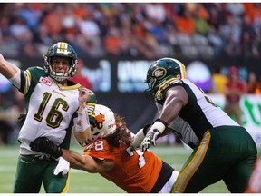 Edmonton Eskimos quarterback Matt Nichols throws the ball as David Menard of the B.C. Lions delivers a hit during a Canadian Football League game against the B.C. Lions at BC Place in Vancouver on Aug. 6, 2015.