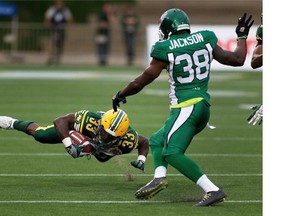 Edmonton Eskimos’ Shakir Bell (33) is tripped up by Saskatchewan Roughriders’ Tristan Jackson (38) during a pre-season game in Fort McMurray on June 13, 2015. It was the most northern game ever played in Canadian Football League history.