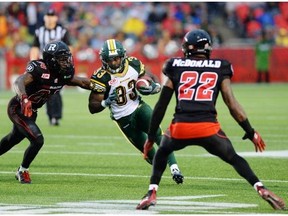 Edmonton Eskimos’ Shakir Bell weaves his way through Ottawa Redblacks’ Jerrell Gavins, left, and Brandon McDonald a game in Ottawa on July 17. The Eskimos offensive line is vastly improved this season, opening up holes for Bell to run through.