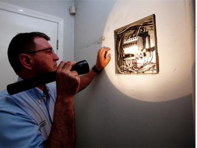 Home inspector Rob Yaworski  checks an electrical panel in a garage.