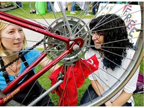 Jana Bockstette (left) tunes up a bicycle owned by Rowan El-Bialy (right) at a celebration held at the University of Alberta campus on Wednesday July 29, 2015. Bicyclists were celebrating ten successful years for the University of Alberta Community Bike Shop.