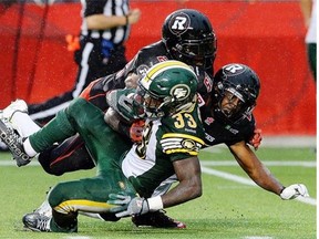 Ottawa Redblacks’ Brandon McDonald, top, and Brandyn Thompson tackle Edmonton Eskimos rookie running back Shakir Bell during Friday’s Canadian Football League game at Ottawa’s TD Place.