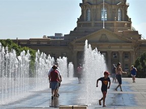 People frolic in the water fountains north of the Alberta Legislature on a warm Sunday afternoon in Edmonton on Aug. 9, 2015.