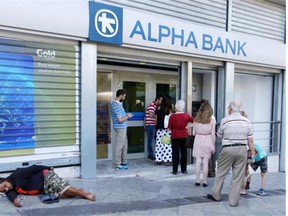 People line up to use an ATM of a bank in Athens as a person begs for alms Monday, July 13, 2015. Greece reached a deal with its European creditors Monday, pledging stringent austerity to avoid an exit from the euro.