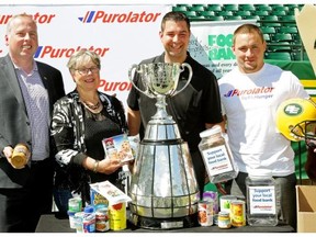 Len Rhodes (President/CEO, Edmonton Eskimos), Marjorie Bencz (Executive Director, Edmonton Food Bank), Brian Collins (Corporate Sponsorship Manager, Purolator) and JC Sheritt (Edmonton Eskimos linebacker) are photographed with the Grey Cup at Commonwealth Stadium in Edmonton on July 30, 2015. Purolator has teamed up with the Edmonton Eskimos to tackle hunger as part of the 13th season of the Purolator Tackle Hunger program. Eskimo fans are asked to bring non-perishable food or cash donations to the game, which will be donated to Edmonton’s Food Bank.