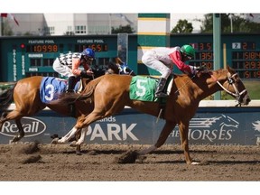 Rico Walcott, riding For Cash, wins the Fred Jones stakes race ahead of Killin Me Smalls ridden by Ruben Lara at Northlands Park racetrack on July 18, 2015 in Edmonton.