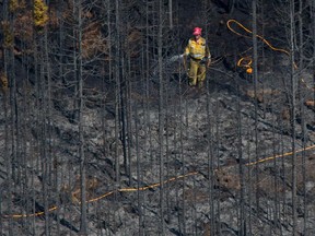 Woodland fire fighters with Alberta Agriculture and Forestry extinguish hot spots in a wildfire approximately 22 kilometres east of Slave Lake, Alta. on May 27, 2015. The province spent $300 million on fighting wildfires so far this year.