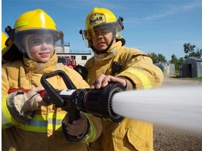 Student Amanda Black gets a helping hand Friday from Lt. James Mcneill of the Spruce Grove Fire Department as part of a hands-on boot camp to draw attention to Norquest College’s new firefighting training program.
