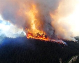 A wildfire rises over a hill in Jasper National Park on July 9, 2015.