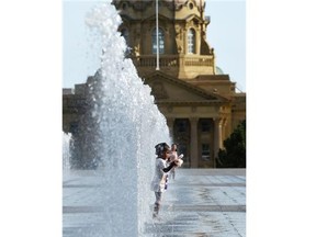 With temperatures hitting 30 C, Tessi Seremba, 2, cooled off in the row of fountains north of the Alberta legislature building in Edmonton on Aug. 3, 2015.