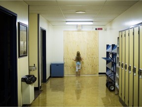 A young student at Frere Antoine Catholic elementary school looks at the now boarded up hallway that used to lead to the portables that burnt down on August 12, 2015. Topher Seguin/Edmonton Journal