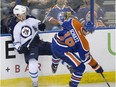 Winnipeg Jets' Adam Lowry (17) is checked by Edmonton Oilers' Justin Schultz (19) during second period NHL pre-season action in Edmonton, Alta., on Sept. 23, 2015.