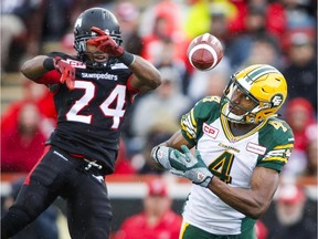 Edmonton Eskimos' Adarius Bowman, right, juggles a pass as Calgary Stampeders' Joe Burnett looks on during second half CFL football action in Calgary on Monday, September 7, 2015.