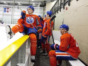 Edmonton Oilers Brandon Davidson, left, jumps the board as Andrej Sekera takes a break on the bench during training camp in Leduc, Alta., on Friday September 18, 2015.