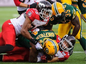 EDMONTON, AB - JULY 24: Cameron Sheffield #94 of the Edmonton Eskimos tackles Rob Cote #26 of the Calgary Stampeders during a CFL game at Commonwealth Stadium on July 24, 2014 in Edmonton, Alberta, Canada. The Eskimos defeated the Stampeders 26-22.