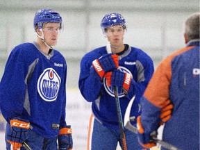 Edmonton Oilers Connor McDavid, left, and Taylor Hall talk with head coach Todd McLellan during training camp in Leduc, Alta., on Friday, Sept. 18, 2015.