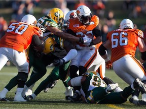 B.C. Lions running back Andrew Harris is tackled by Edmonton Eskimos' Eddie Steele, bottom, and Dexter McCoil during a Canadian Football League pre-season game at Vancouver on June 19, 2015.