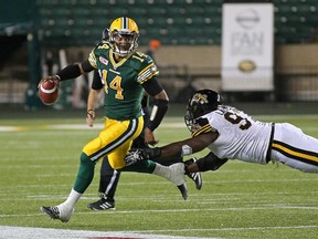 Edmonton Eskimos quarterback James Franklin, left, eludes a tackle by Hamilton Tiger-Cats' Ted Laurent during CFL game action in Edmonton on Aug. 21, 2015.