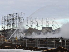 Firefighters put out hotspots at a fire in a condo development under construction in Windermere in Edmonton on Saturday, March 15, 2014.