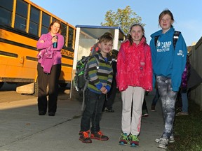 Andrea Floyd, back left, waits for the school bus with her children Carter, 7, Abigail, 9, and Ella, 11, in Edmonton's Ellerslie Crossing neighbourhood. The Floyd family was one of hundreds dramatically affected when exploding student numbers and planning decisions converged to create a dilemma in the city's outer neighbourhoods.