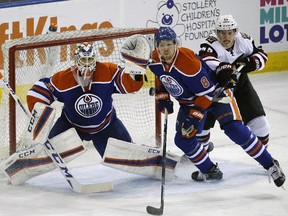 Edmonton Oilers goalie Anders Nilsson looks for the puck as Arizona Coyotes' Henrik Samuelsson, right, and Edmonton Oilers' Griffin Reinhart skate to the net during first-period pre-season NHL action at Rexall Place on Sept. 29, 2015.