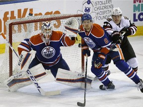 Edmonton Oilers goalie Anders Nilsson (left) looks for the puck as Arizona Coyotes Henrik Samuelsson (right) and Edmonton Oiler Griffin Reinhart (middle) skate to the net during first period pre-season NHL action in Edmonton on September 29, 2015.