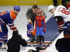 Mable Tooke (6-years-old), aka. Spider-Mable, prepares to drop the ceremonial face-off puck with assistance from Edmonton Oilers captain Andrew Ference before the pre-season NHL game between the Edmonton Oilers and the Arizona Coyotes in Edmonton on September 29, 2015. Oilers Jordan Eberle (left) and Coyotes Mikkel Boedker (right) participated in the face-off.