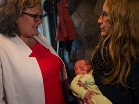 Alberta Health Minister Sarah Hoffman speaks Tuesday with Amy Wilson about her nine-day old son, Oscar, at the Lucina Centre, a private birthing centre used by midwives.