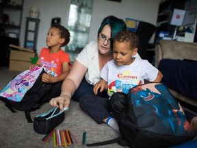 Evangeline Cole helps prepare her two children, Matthew, left, and Darian for school while at in their Edmonton apartment on Saturday.