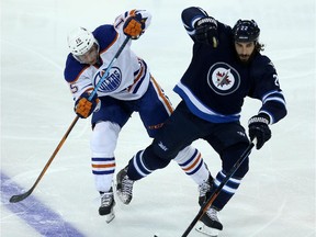 Edmonton Oilers Tyler Pitlick (15) collides with Winnipeg Jets Chris Thorburn (22) during first period pre-season NHL hockey action in Winnipeg, Friday, September 25, 2015.