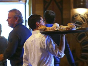 In this file photo, a server carries a tray of food at an Ivar's restaurant in Seattle, WA. After Seattle's new minimum wage law took effect April 1, 2014, Ivar’s Seafood Restaurants announced that it was jacking up its prices by about 21 percent, eliminating tipping as a routine procedure, and immediately paying all its hourly workers a $15 per hour. They began the new pay rate three years earlier than the law required.