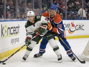 Minnesota Wild's Jordan Schroeder and Edmonton Oilers' Darnell Nurse battle for the puck behind the net during the second period of an NHL pre-season hockey game in Saskatoon, Saturday, September 26, 2015.