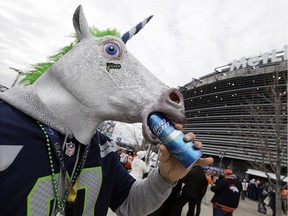 Kellan Smalley of Bremerton, Wash., dons a unicorn head and drinks a beer outside MetLife Stadium before the NFL Super Bowl XLVIII football game between the Seattle Seahawks and the Denver Broncos, Sunday, Feb. 2, 2014, in East Rutherford, N.J.