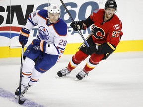 Edmonton Oilers' Lauri Korpikoski, left, and Calgary Flames' Dougie Hamilton chase the puck during NHL pre-season split-squad hockey action in Calgary on Sept. 21, 2015.