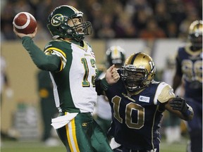 Edmonton Eskimos' quarterback Mike Reilly, left, gets a pass away under pressure from Winnipeg Blue Bombers' Henoc Muamba during first half CFL action in Winnipeg on Friday, September 20, 2013.