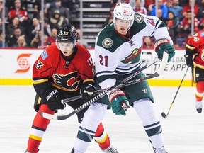 The Minnesota Wild’s Kyle Brodziak, right, towers over Johnny Gaudreau of the Calgary Flames during a National Hockey League game at the Scotiabank Saddledome in Calgary on Jan. 29, 2015.