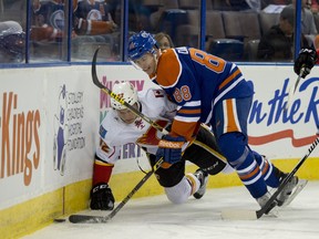 Brandon Davidson of the Edmonton Oilers, knocks down Austin Carroll of the Calgary Flames at Rexall Place.  Shaughn Butts / Edmonton Journal