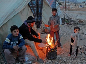 Refugee Syrian family  try to keep warm by their UN supplied tent near the village of Raheed, in Lebanon's eastern mountains, on Dec. 1. 2013. Refugees flooded into Lebanon initially because of Syria's civil war.