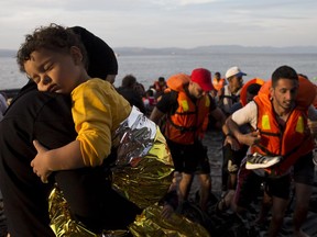 Syrian refugees arrive on a dinghy after crossing from Turkey to Lesbos island, Greece, Wednesday, Sept. 9, 2015. The head of the European Union's executive says 22 of the member states should be forced to accept another 120,000 people in need of international protection who have come toward the continent at high risk through Greece, Italy and Hungary.