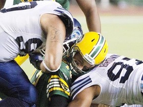 Toronto Argonauts defensive lineman Cleyon Laing, left, and Ivan Brown catch Edmonton Eskimos quarterback Mike Reilly in a sandwich hit during a Canadian Football League game at Commonwealth Stadium on Sept. 28, 2013. Reilly suffered a concussion on the play.