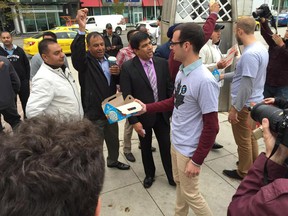 Uber employee Jean-Christophe de Le Rue hands out Timbits to taxi drivers during rallies outside City Hall about a proposed ride-sharing bylaw.