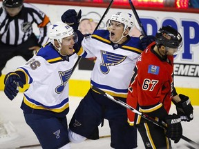 St. Louis Blues' Scottie Upshall, center, celebrates his goal with teammate Paul Stastny, left, as Calgary Flames' Michael Frolik, from the Czech Republic, skates by during the first period of an NHL hockey game Tuesday, Oct. 13, 2015, in Calgary.