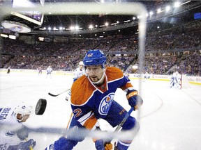 Vancouver Canucks' Alex Biega (55) falls as Edmonton Oilers' Anton Slepyshev (42) goes for the loose puck during pre-season action in Edmonton on Oct. 1, 2015.