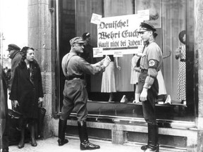 Members of the paramilitary wing of the Nazi party post signs on a Jewish store in Berlin warning Germans not to buy from Jews.