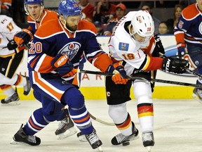 Luke Gazdic of the Edmonton Oilers, left, and David Jones of the Calgary Flames tangle while Connor McDavid looks on at Rexall Place on Sept. 21, 2015.